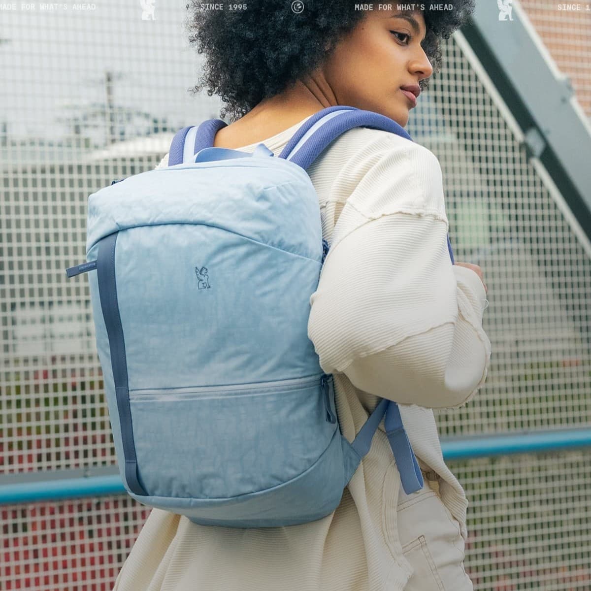 Person wearing a light blue backpack with a blurred background